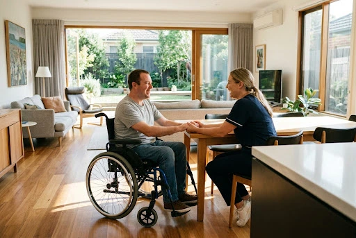 A friendly care worker assisting an NDIS participant in a bright, modern living room.